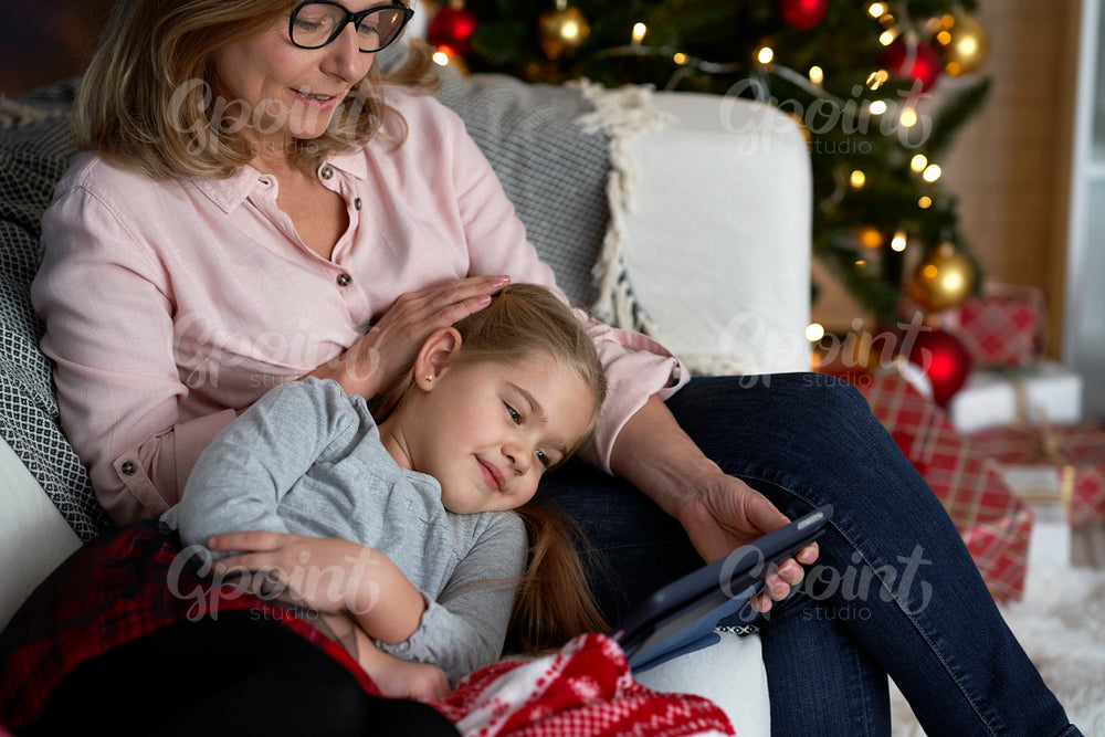Grandmother with granddaughter watching cartoons on the tablet