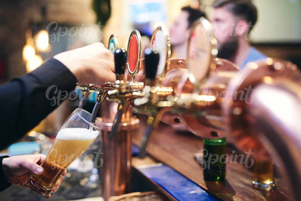 Bartender's hand pouring customer a mug of cold beer