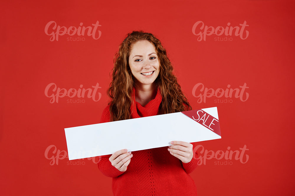 Smiling girl showing empty banner of sale