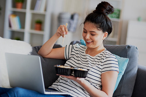 Young Asian woman eat lunch and watching something on laptop.