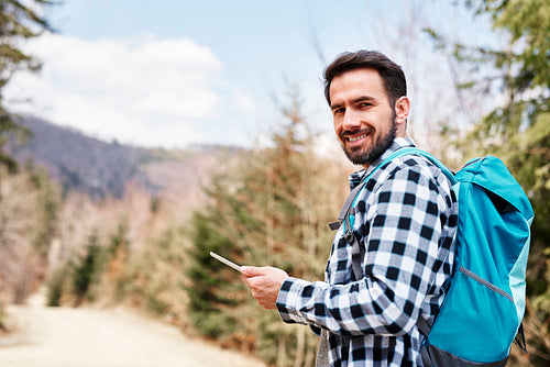 Portrait of smiling hiker using mobile phone during hiking trip
