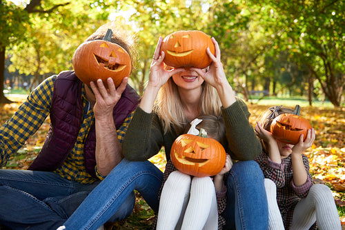 Family holding halloween pumpkins in front of their face