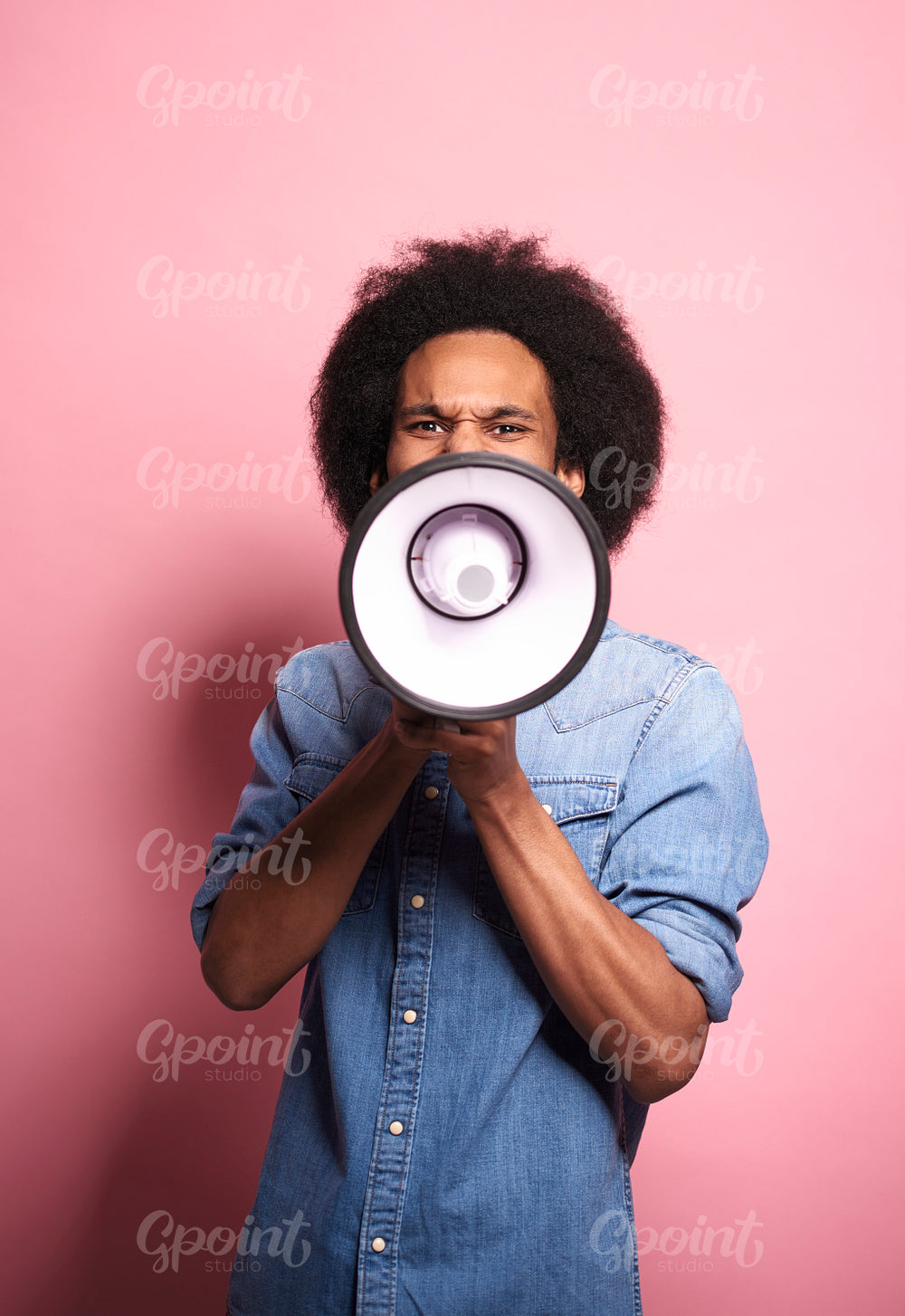 Young African man shouting through a megaphone in studio shot.
