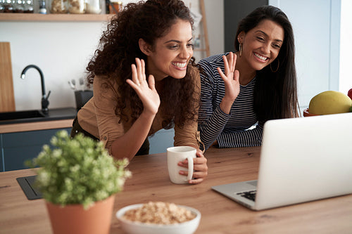 Happy women waving during a video conference