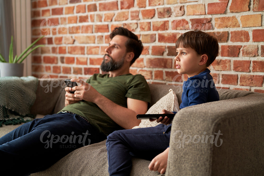 Father and son watches TV together at home