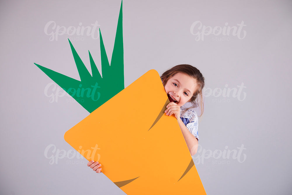Playful girl eating a big carrot