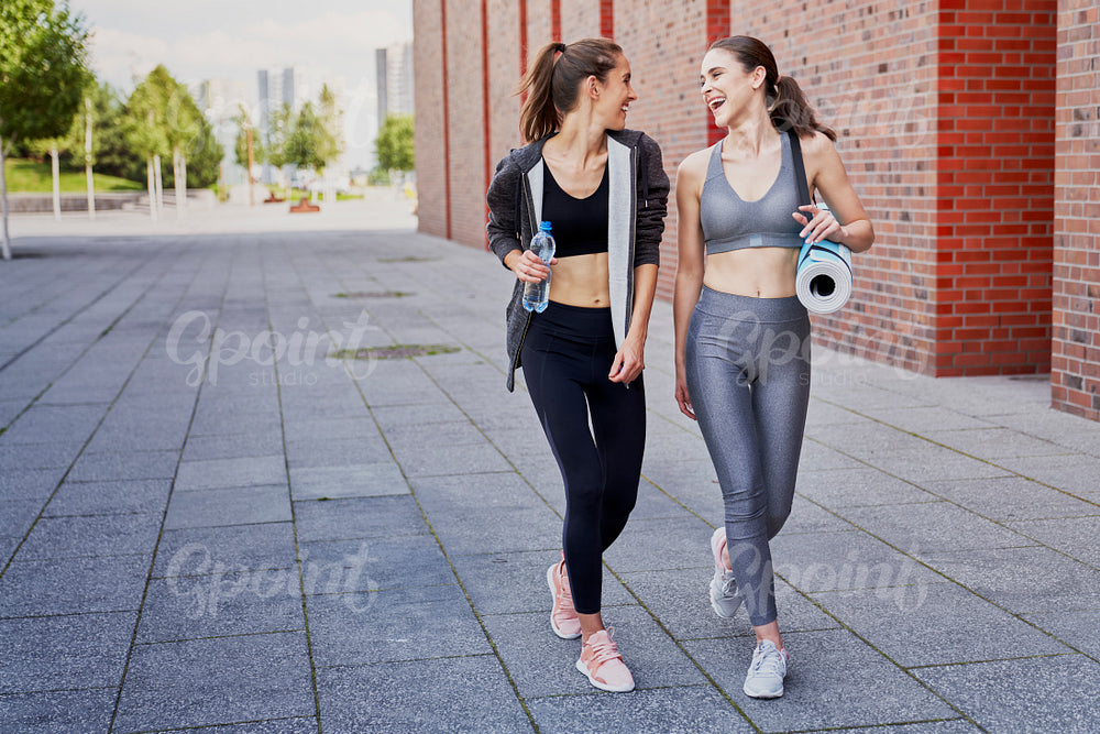 Two laughing athletic women come back from training