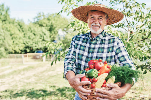 Portrait of farmer with a basket full of seasonal vegetables