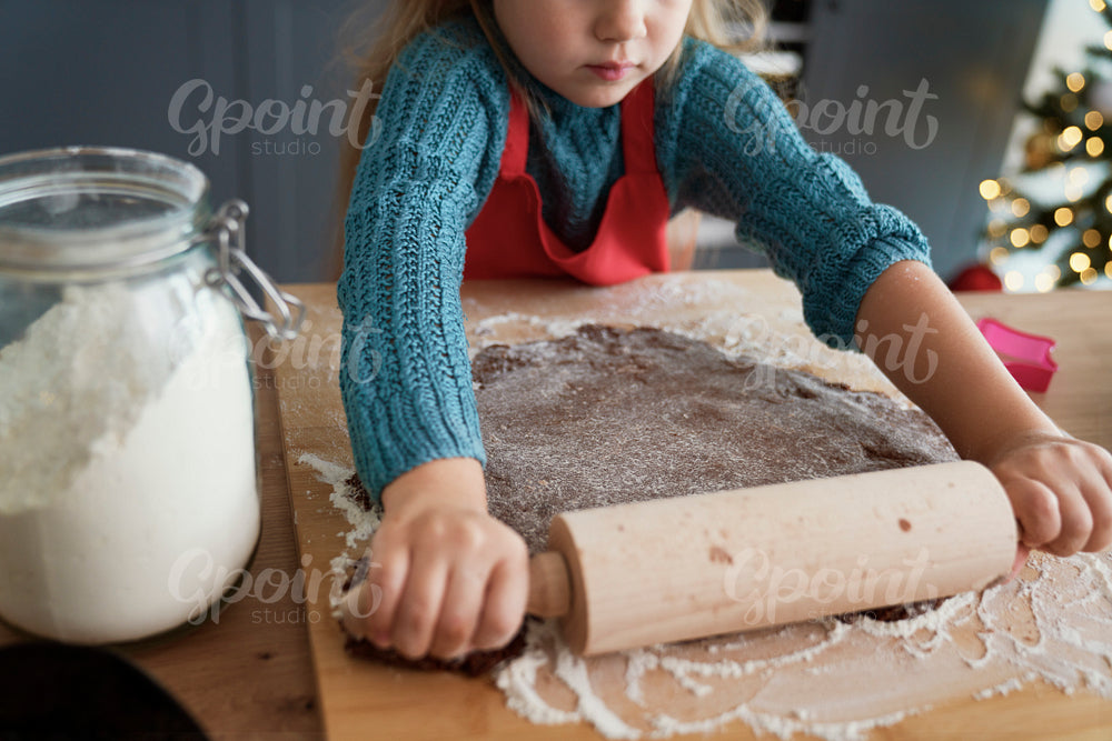Girl rolling gingerbread pastry for homemade cookies