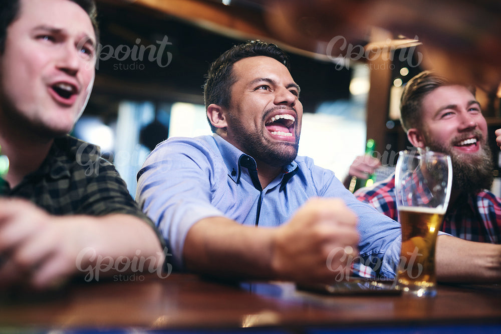 Excited football fans watching american football in the pub
