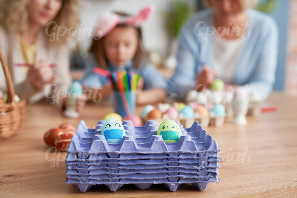 Eggs with face masks on a family background
