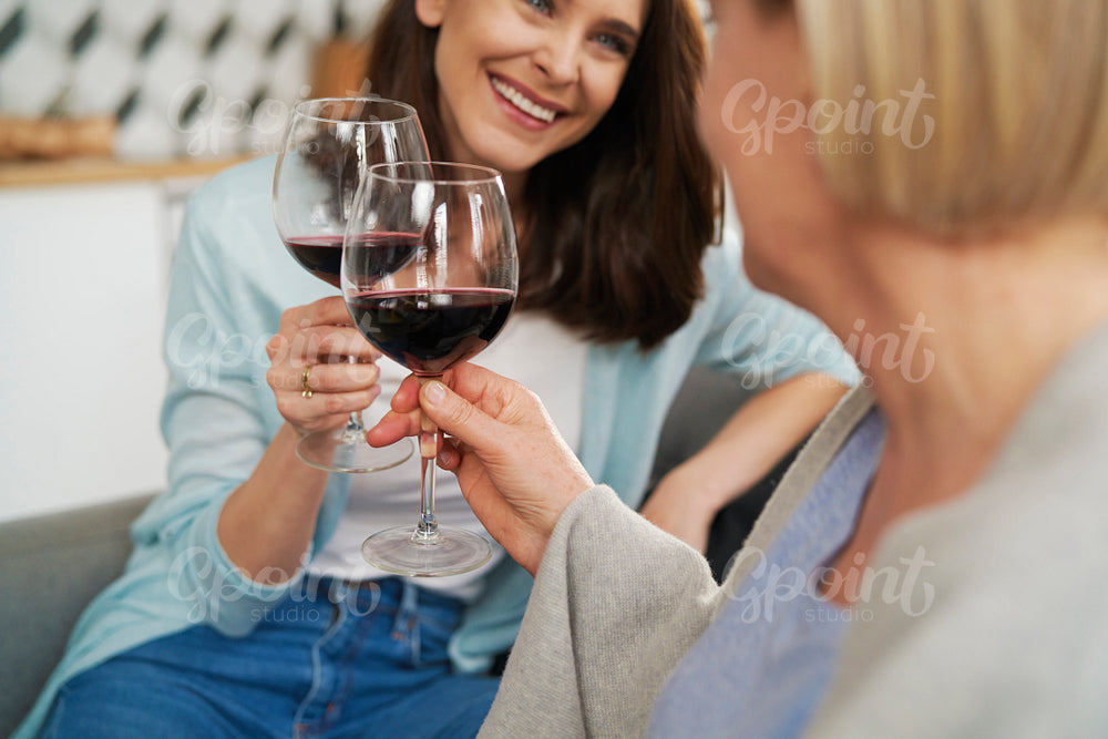 Close up of mother and adult daughter toasting in wine