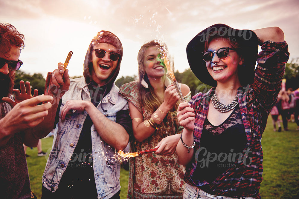 Group of friends holding fireworks at festival