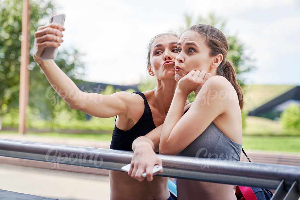 Two athletic women making funny faces for selfies