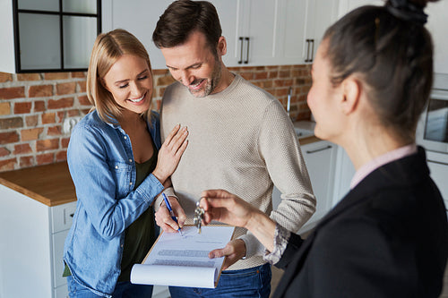 Couple with real estate agent signing contract of new apartment