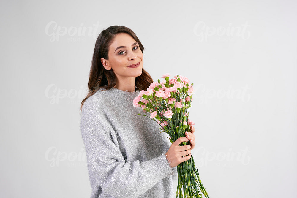 Smiling woman holding bunch of flowers in studio shot