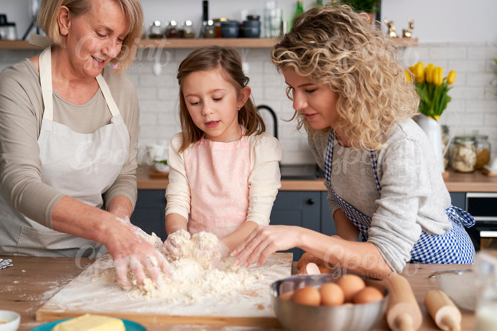 Little girl with mom and grandma making dough
