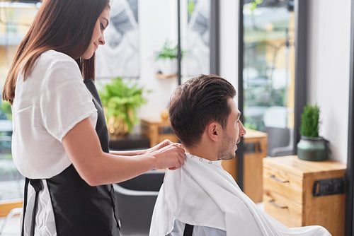 Side view of female hairdresser and man in hair salon
