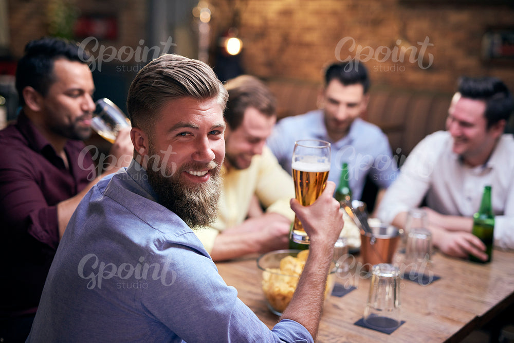 Man drinking beer in pub and friends in the background