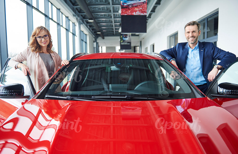 Portrait of mid couple with red car