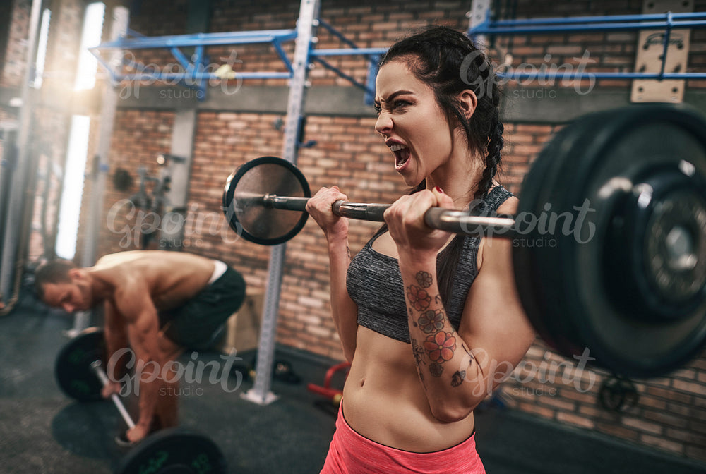 Fit couple lifting barbells in the gym