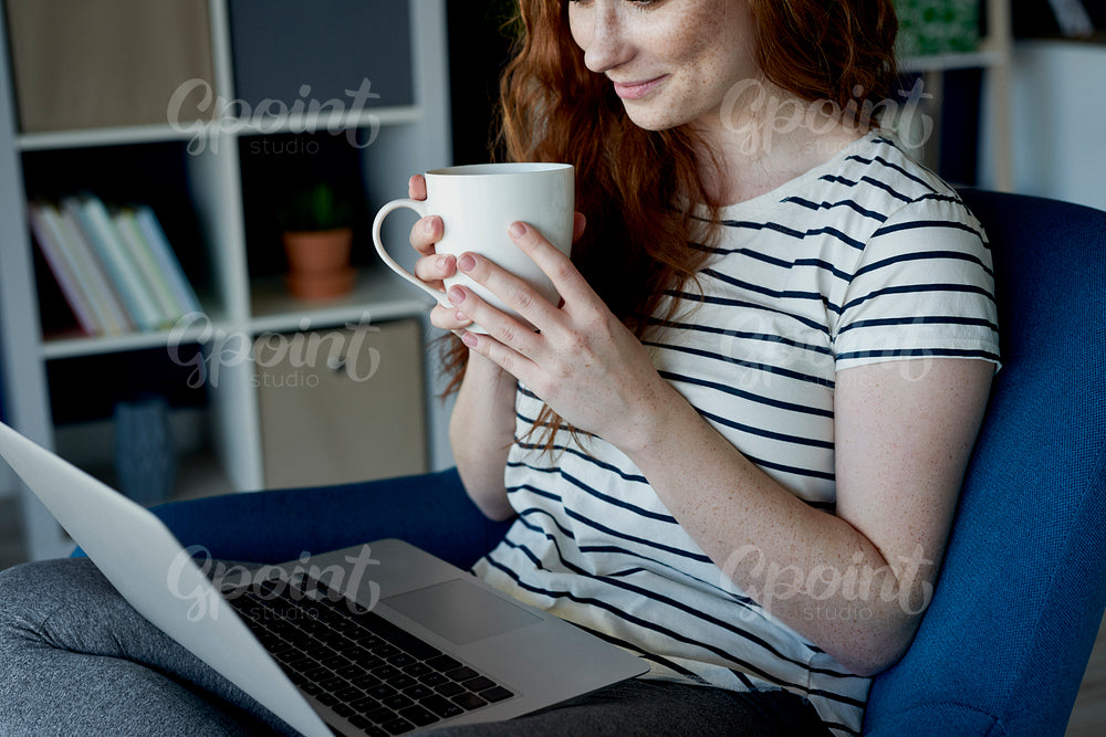 Woman drinking coffee and using her computer