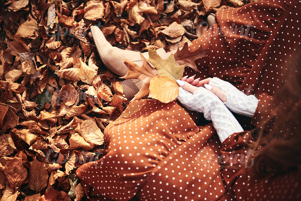 Woman sitting with a bunch of autumnal leaves