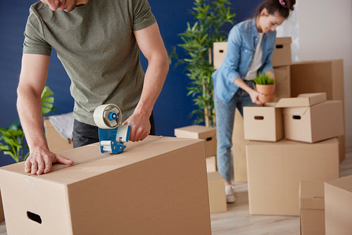 Couple packing cardboard boxes while moving house