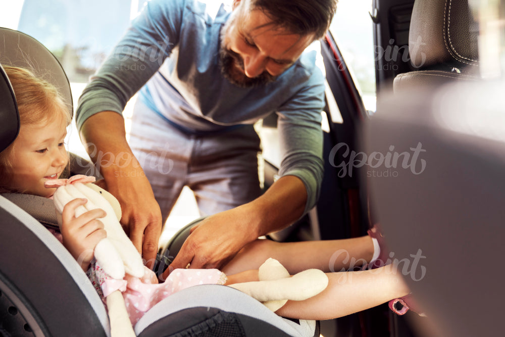 Side view of father securing child to a baby car seat
