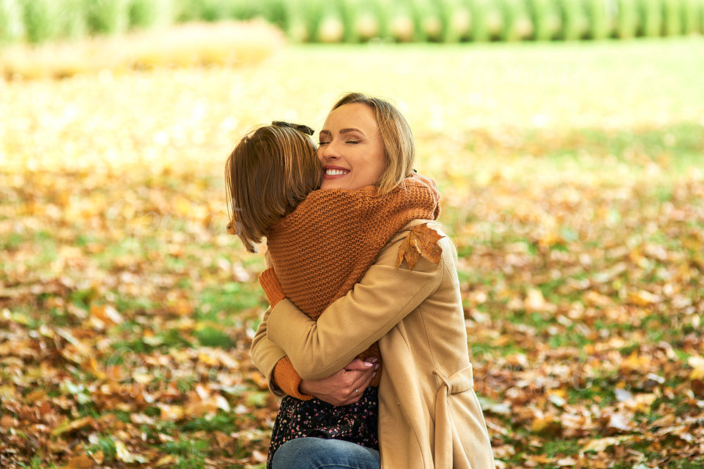 Child embracing mommy in the autumn woods