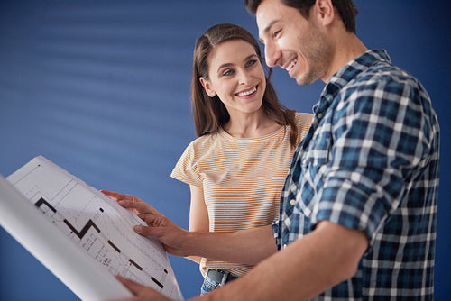Couple browsing blueprint of newly bought house