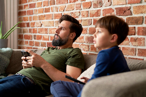 Close up of father and son watches TV together at home