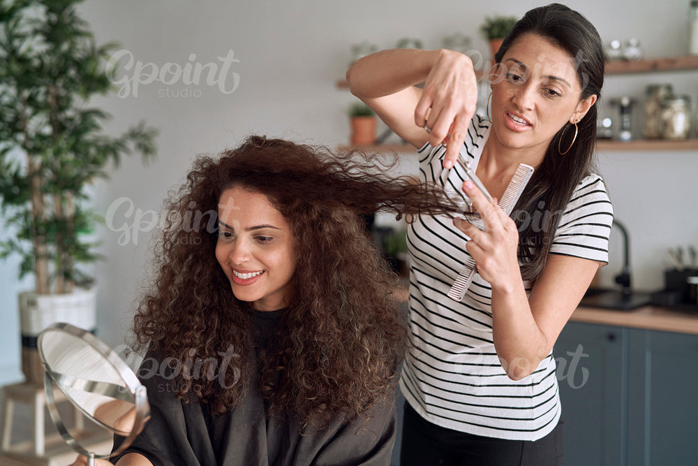 Happy women while trimming their hair at home