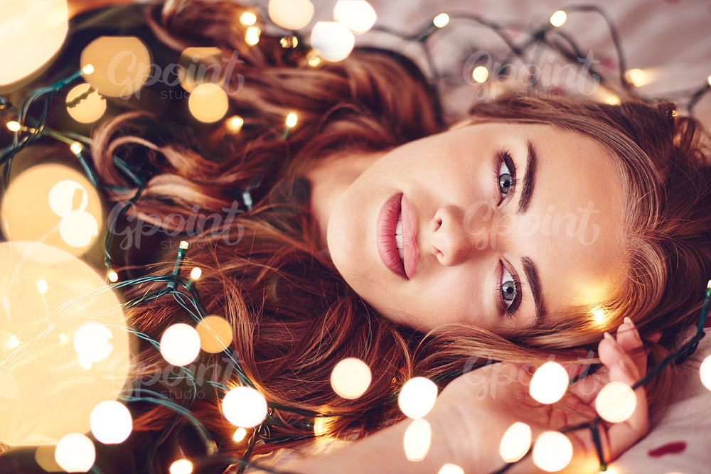 Woman wrapped in christmas lights lying on back