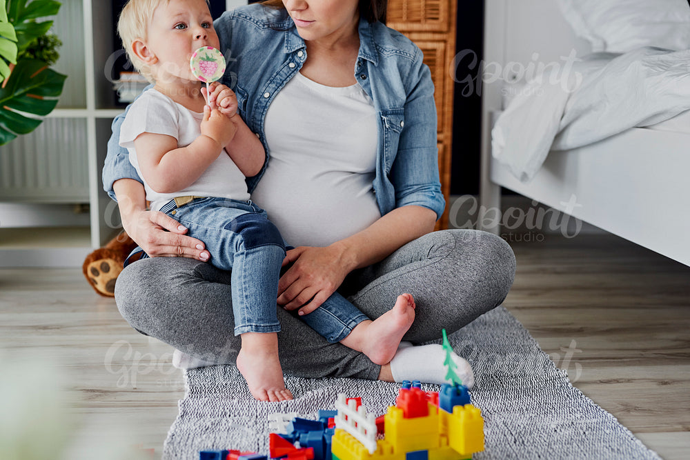 Toddler boy with lollipop and his pregnant mother
