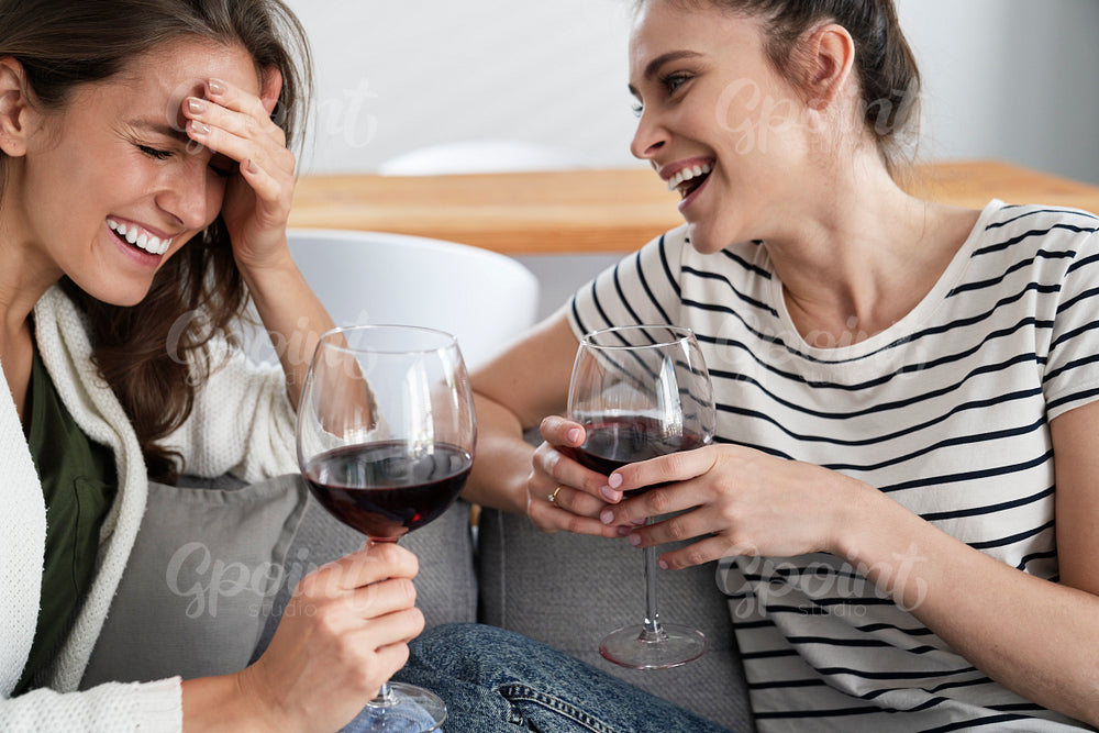 Two friends laughing with a glass of wine in hand