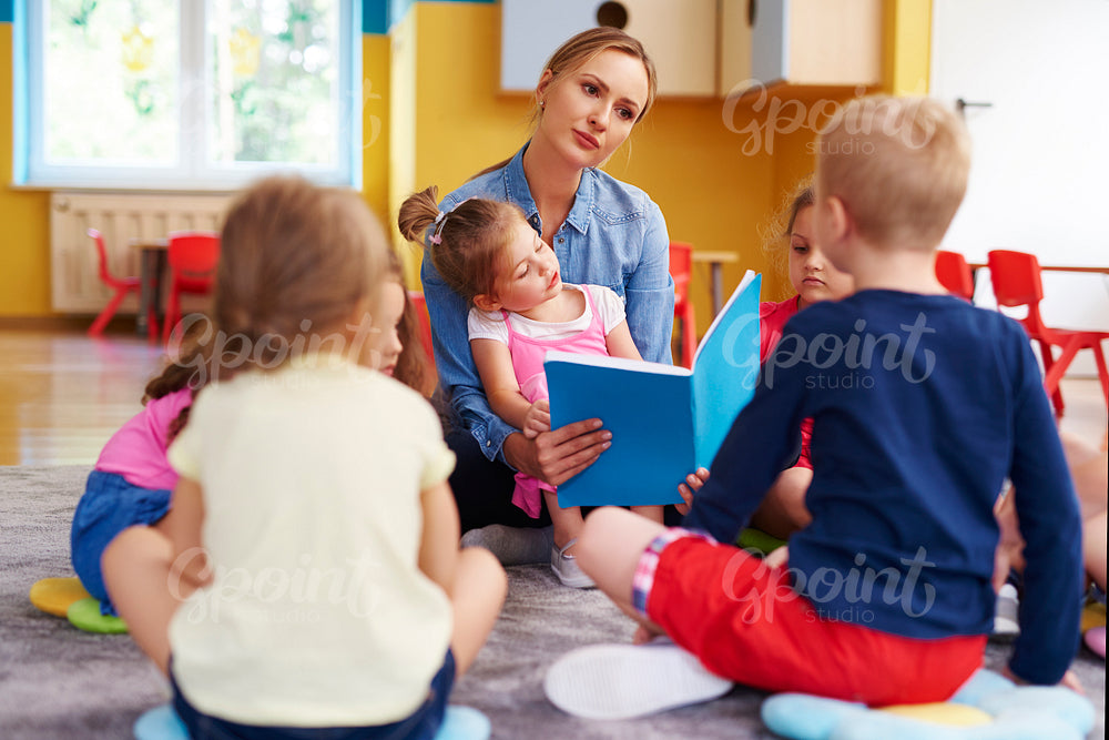 Preschool teacher is reading a book