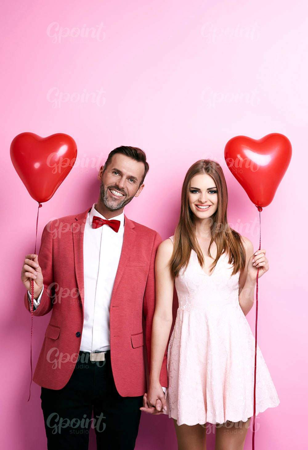 Affectionate couple with heart shape balloons holding hands