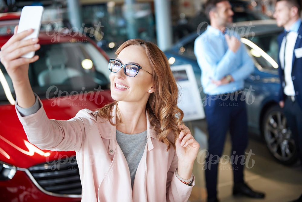 Young woman taking picture in the car dealership