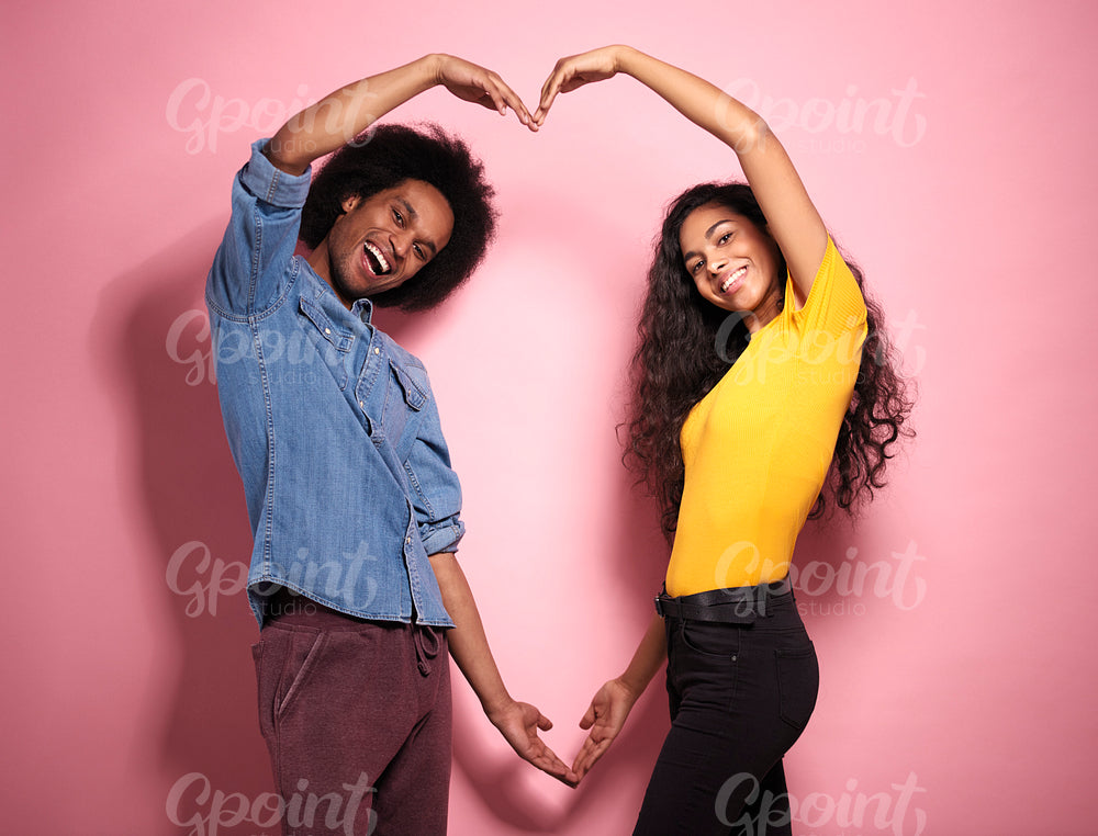 Smiling young African couple making a heart with hands.