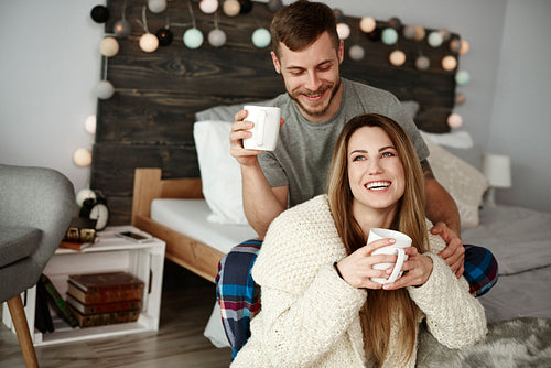 Cheerful couple with coffee enjoying at bedroom