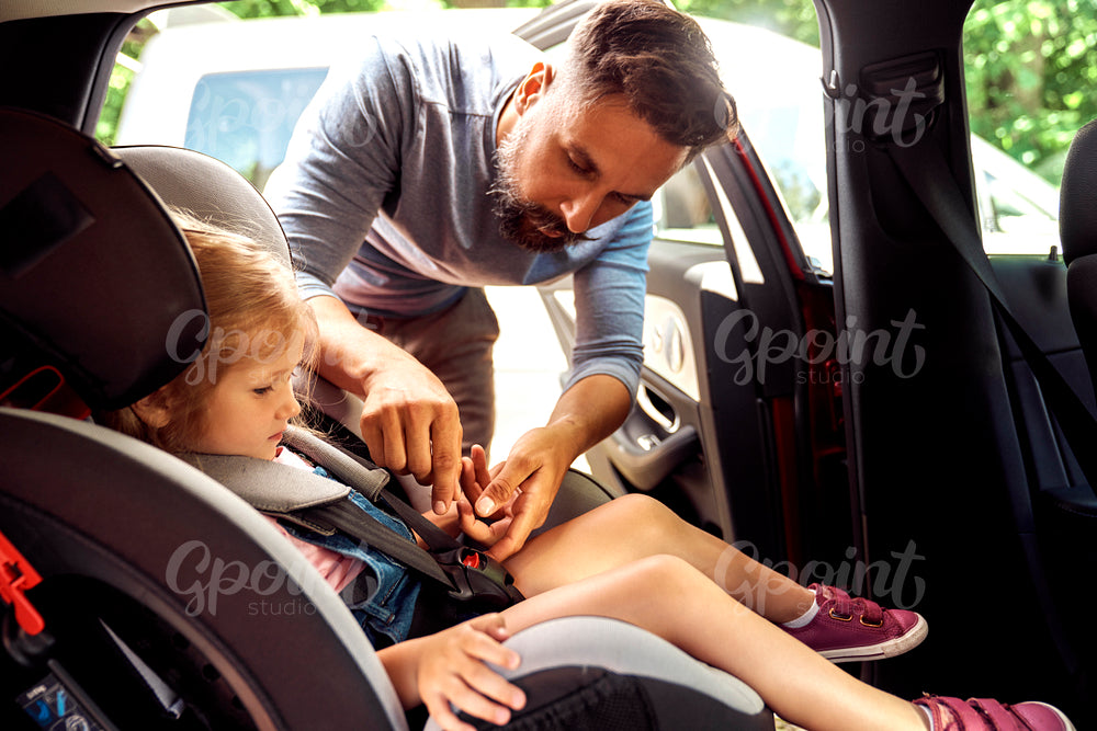 Father securing daughter to a baby car seat