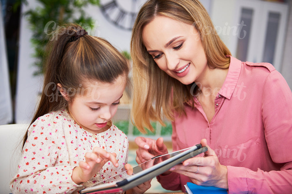 Girl and her young mother using a tablet at home