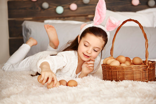Happy child playing with eggs in bedroom