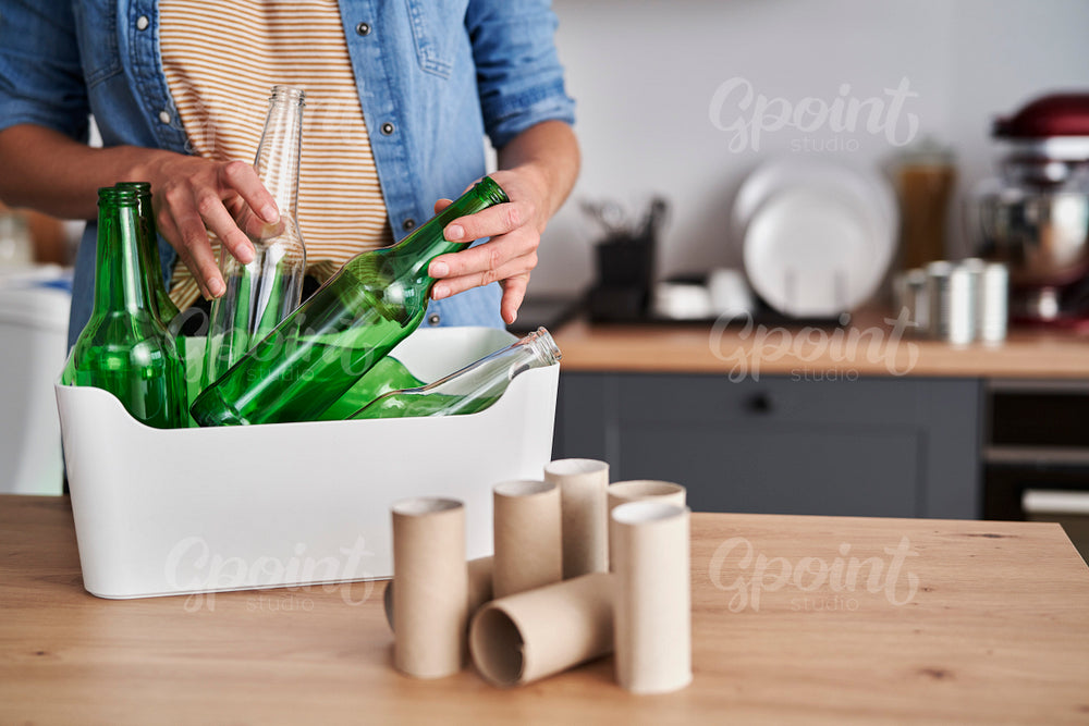 Woman recycling glass garbage in the kitchen