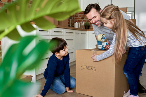Children help their father packing cardboard boxes for the move