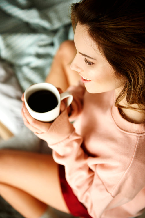 Woman holding coffee mug at bedroom