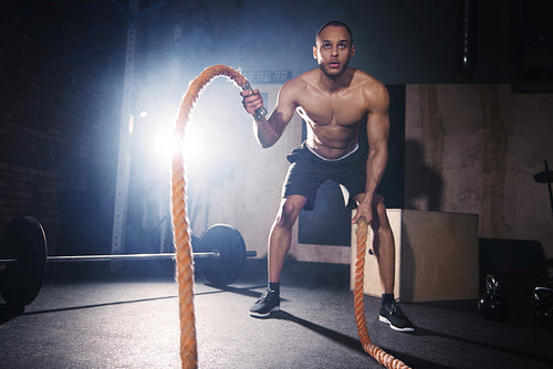 Motivated man throwing ropes at healthy club