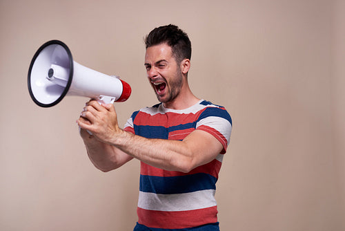 Screaming man with megaphone in studio shot