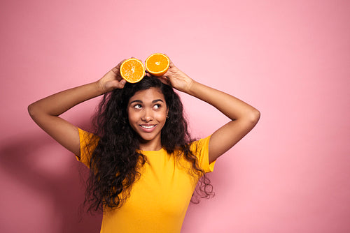 Young African woman having fun with oranges in studio shot